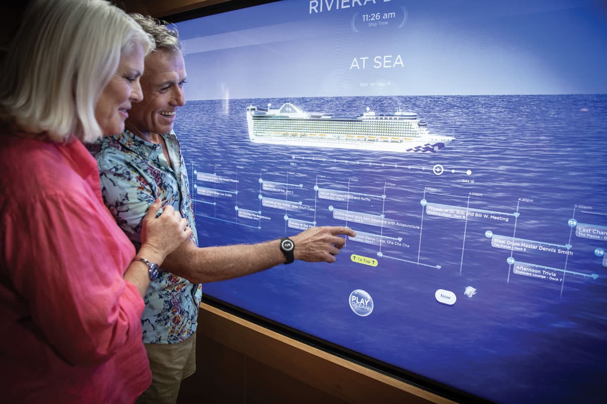 Two guests using the Princess Cruises interactive touchwall to explore their voyage.